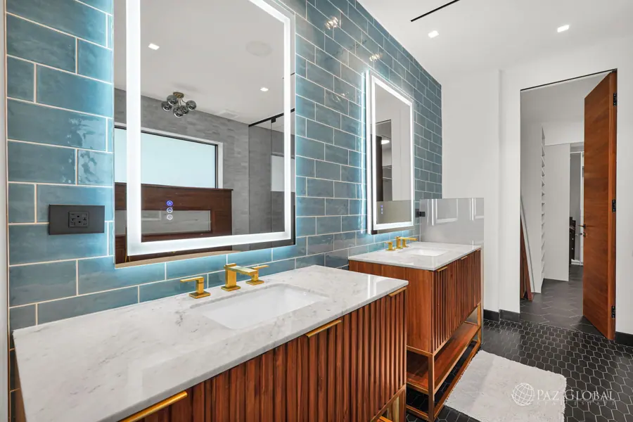Primary bath double vanity with lit mirrors and walnut cabinets